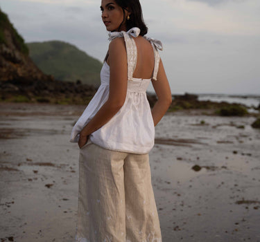 The Nori trousers are an elastic waisted 100% linen pant for a comfortable easy fit, with finishing including real natural pearl and gold plated charms at the end of the belt ties.  Embroidery designed by Fleur Kakasi at the hem. 