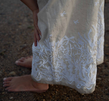 The Nori trousers are an elastic waisted 100% linen pant for a comfortable easy fit, with finishing including real natural pearl and gold plated charms at the end of the belt ties.  Embroidery designed by Fleur Kakasi at the hem. 